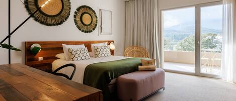 Un dormitorio moderno con una cama de madera, un edredón verde y vistas al exterior a través de amplios ventanales.