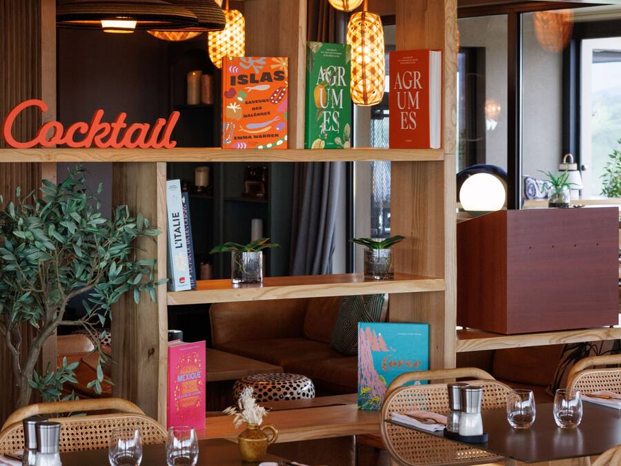 A cozy bar area with wooden shelves, hanging lamps, and wicker furniture.