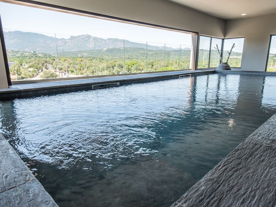 Een binnenzwembad, ligstoelen bij het zwembad