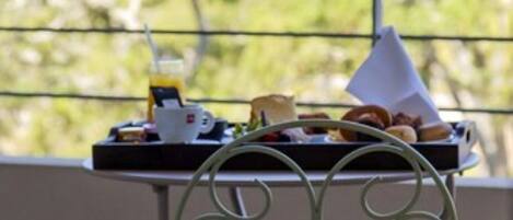A balcony with a table set for breakfast, overlooking a mountainous landscape.