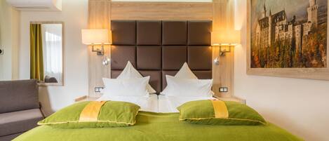 Habitación de hotel con una cama grande, dos lámparas de noche, un cuadro en la pared y un sofá.