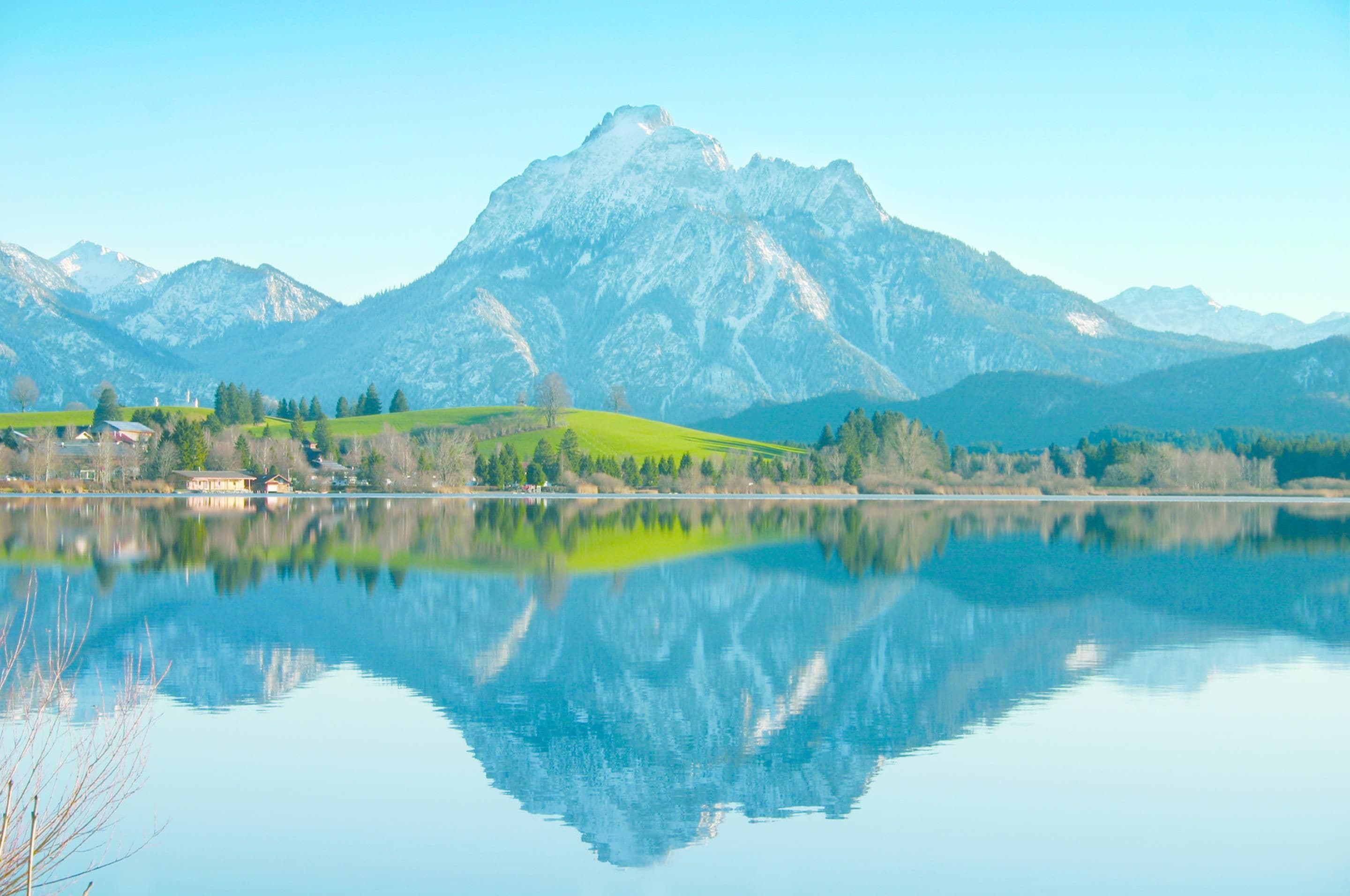 Un lac paisible, avec une chaîne de montagnes en arrière-plan et un petit village sur la rive opposée.