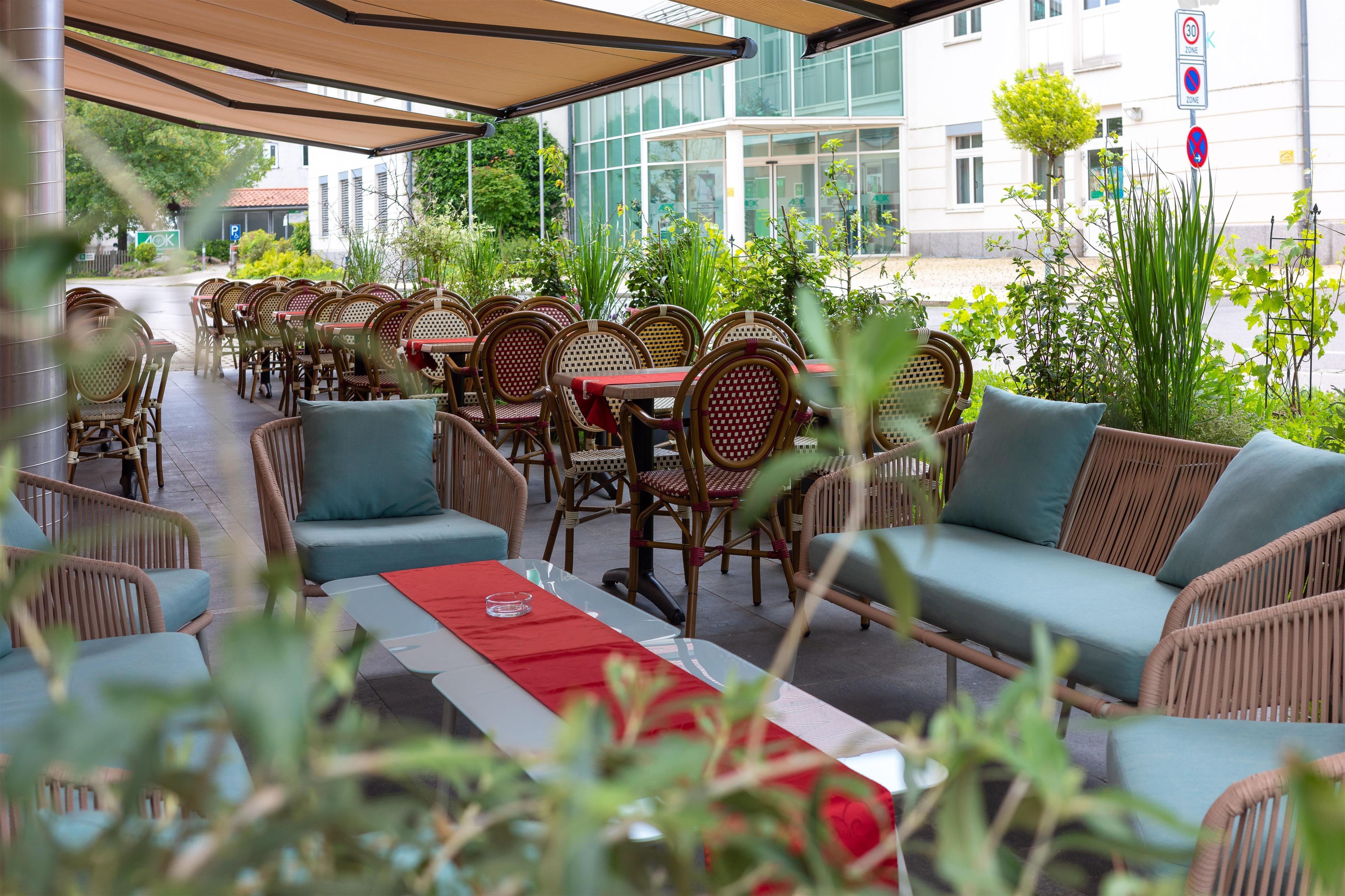 An outdoor seating area with wicker furniture and a red table runner.