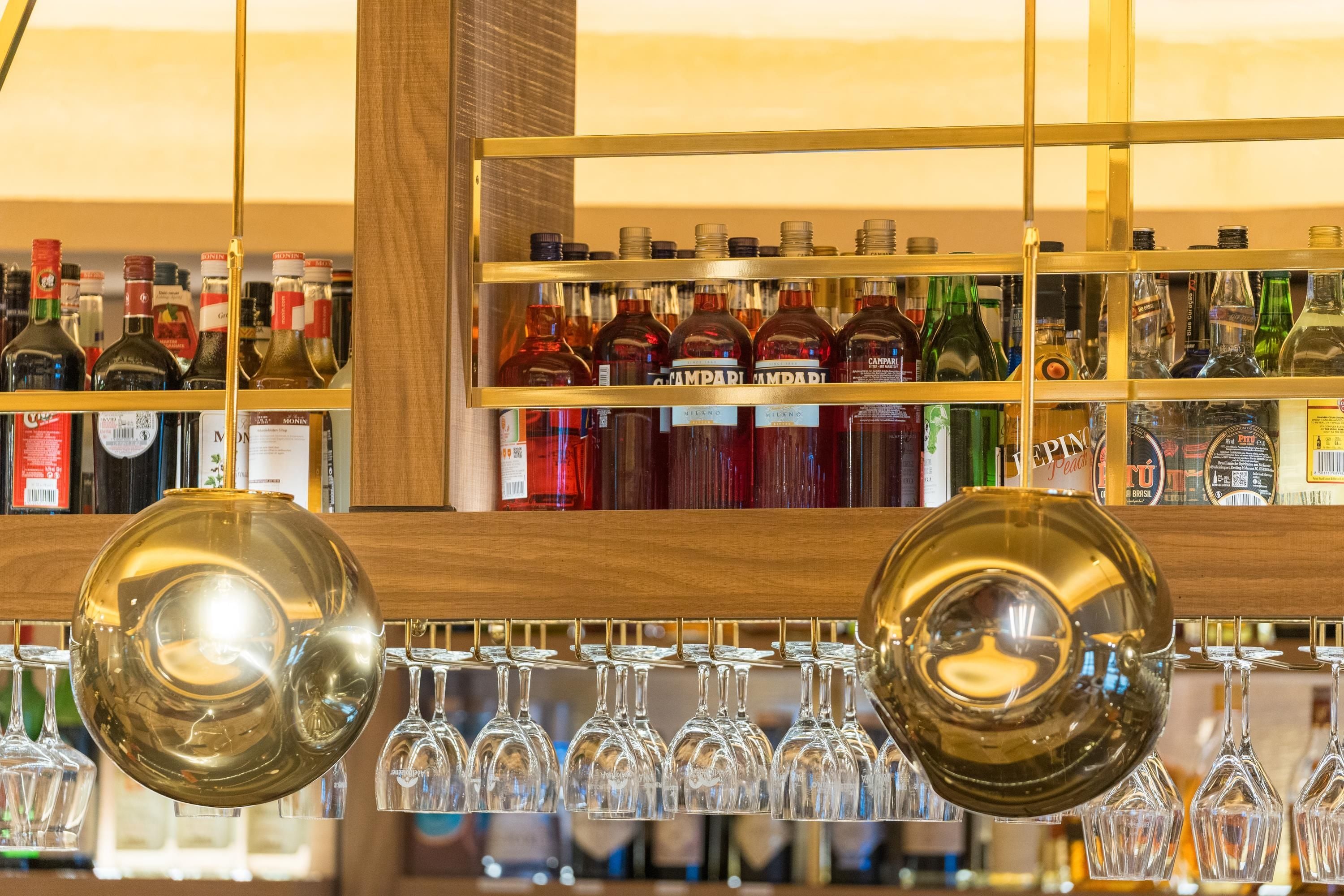 A bar area with shelves of liquor bottles and a selection of wine glasses.