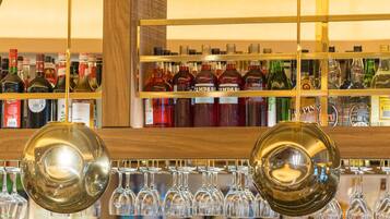 A bar area with shelves of liquor bottles and a selection of wine glasses.