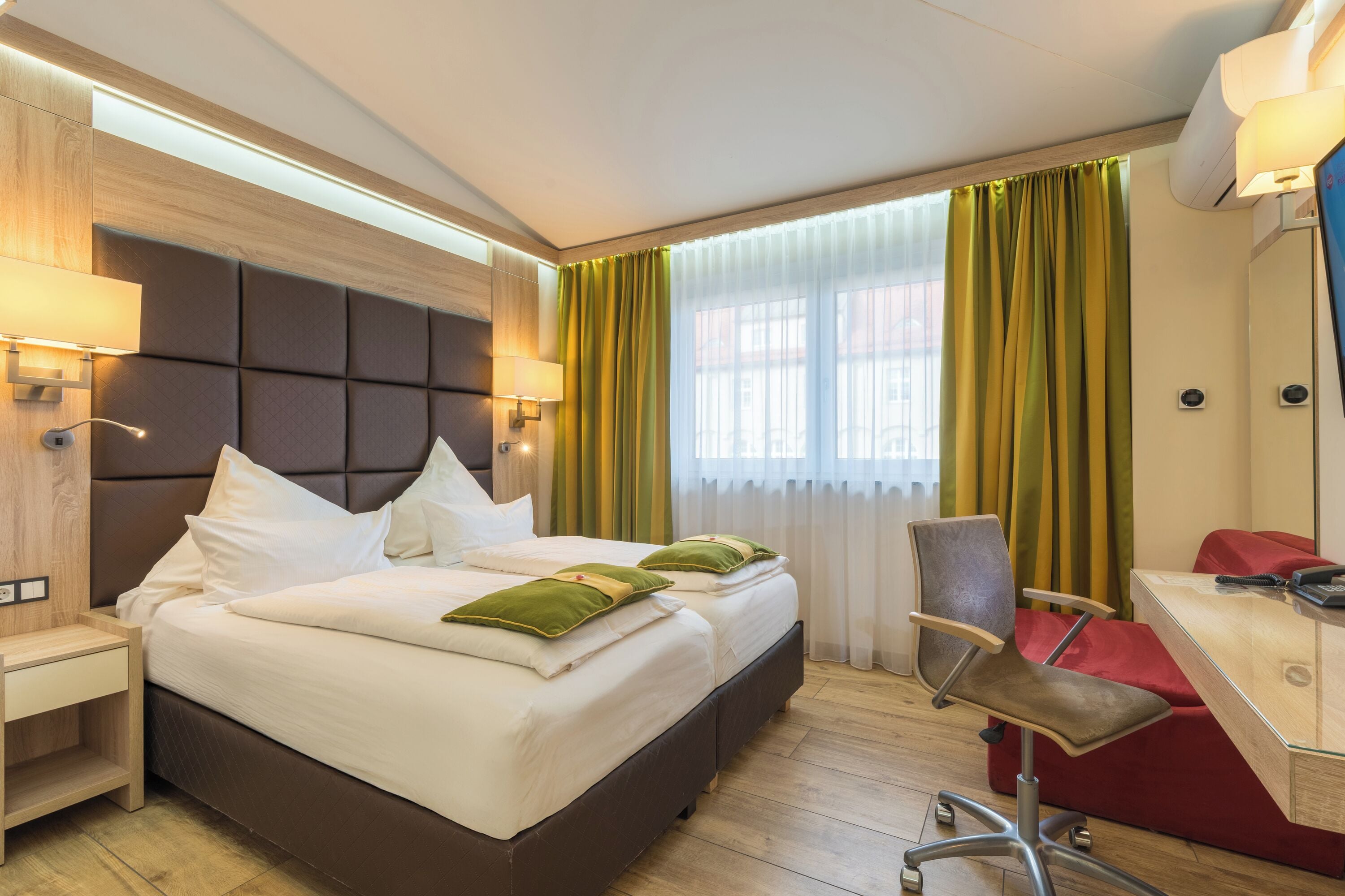 Ein Hotelzimmer mit einem großen Bett, einem Schreibtisch und einem Stuhl.