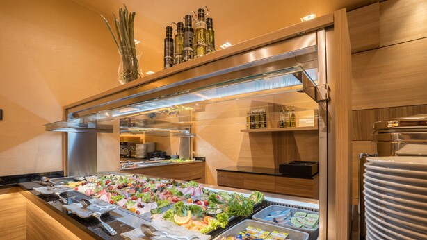 Un buffet proposant une variété de plats, un bar à salades, ainsi qu'un assortiment de condiments et de boissons.