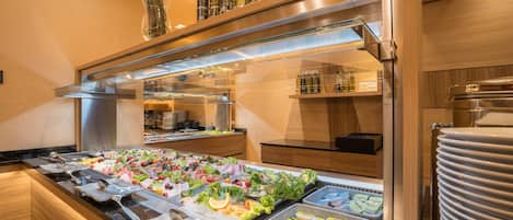 Un bufé con diversas opciones de comida, una barra de ensaladas y una selección de salsas y bebidas.