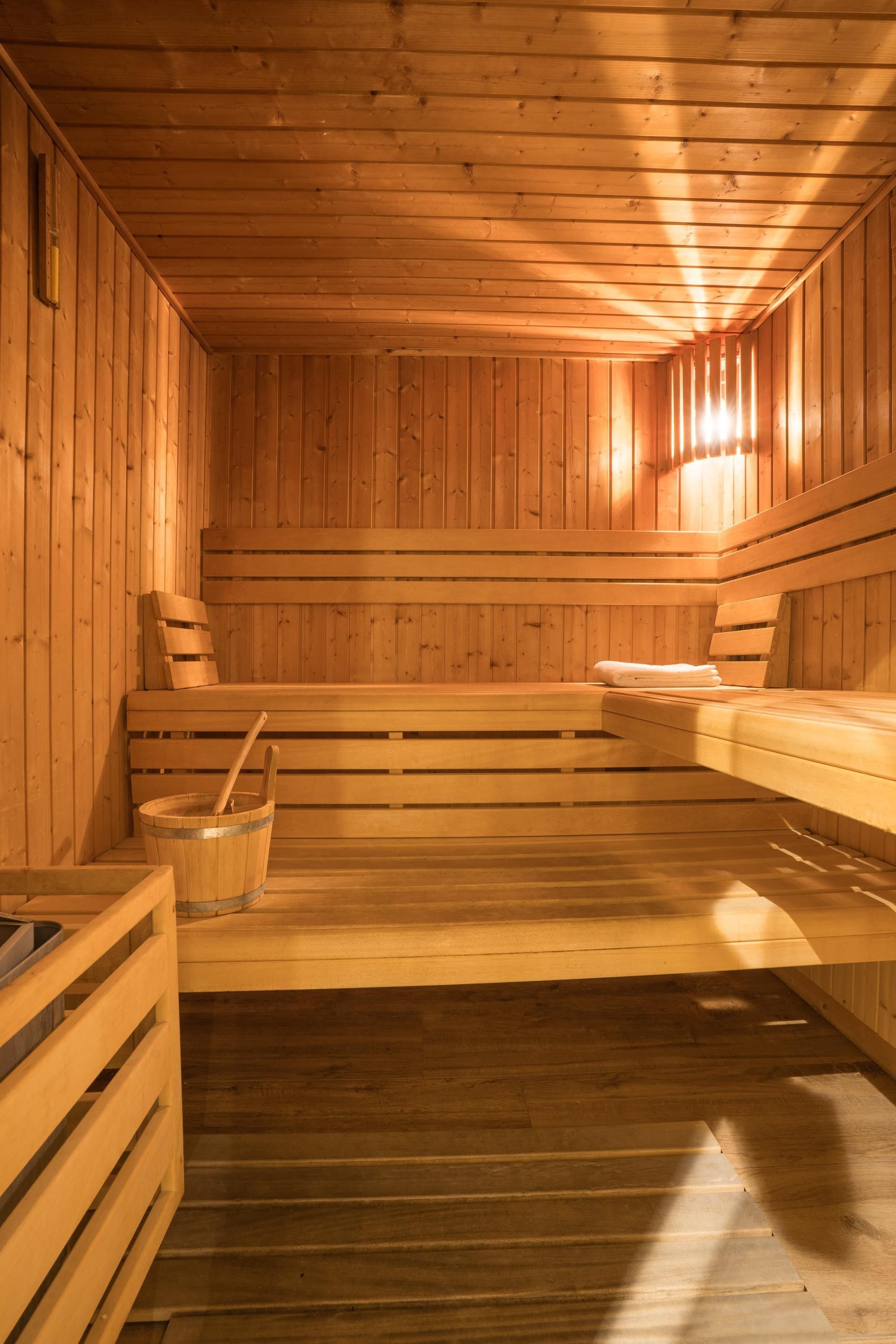 A sauna with wooden benches and a bucket.