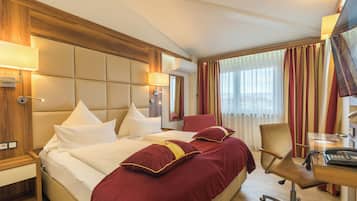 A hotel room with a large bed, a desk, and a chair.