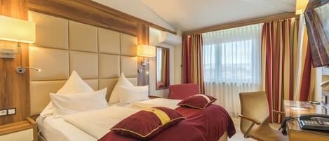 A hotel room with a large bed, a desk, and a chair.