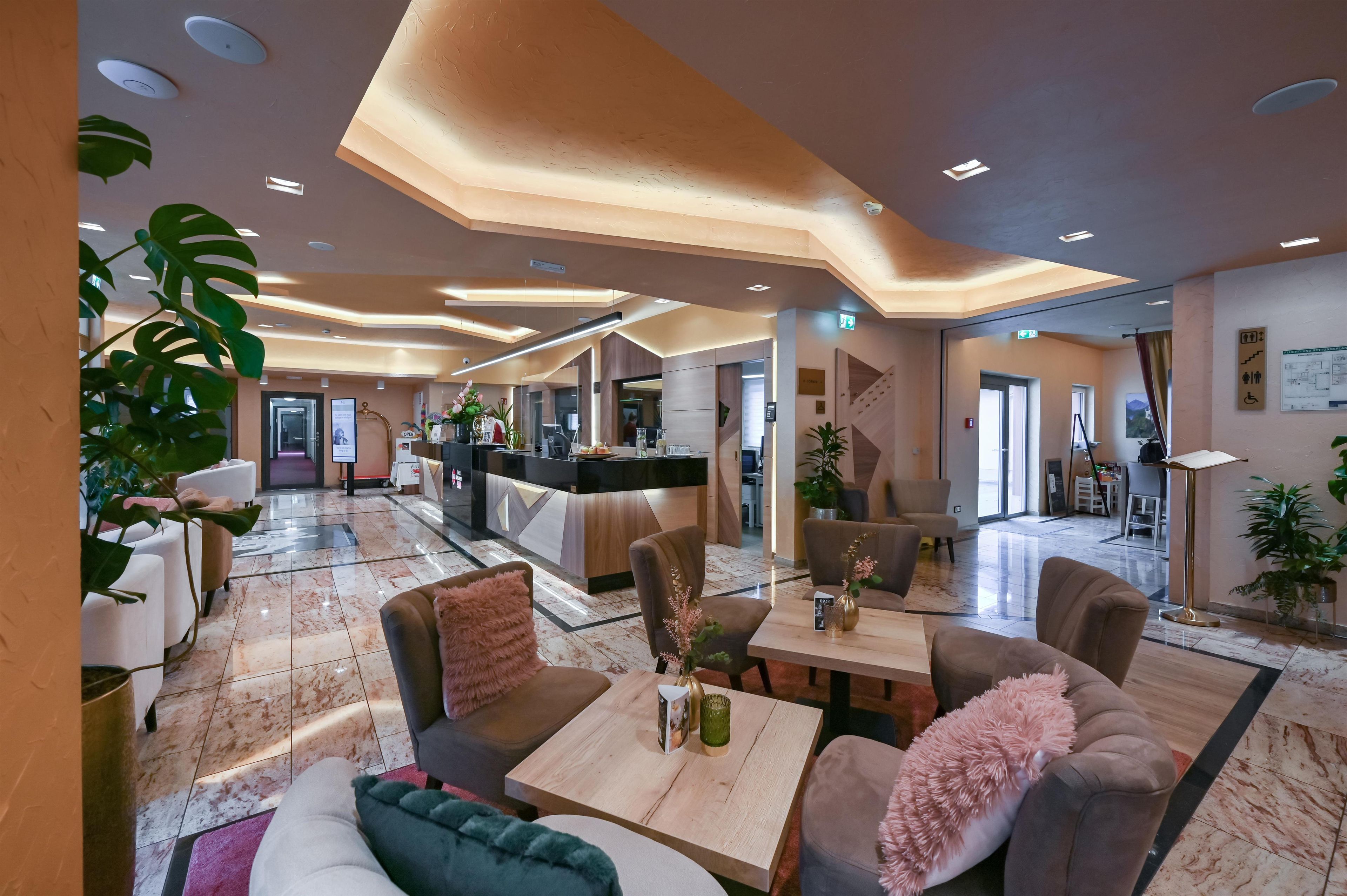 Un hall de hotel con mostrador de recepción, zona de estar y vistas al comedor.
