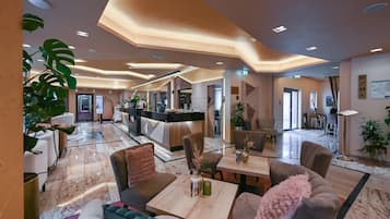A hotel lobby with a reception desk, seating area, and a view into the dining area.