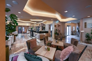 A hotel lobby with a reception desk, seating area, and a view into the dining area.