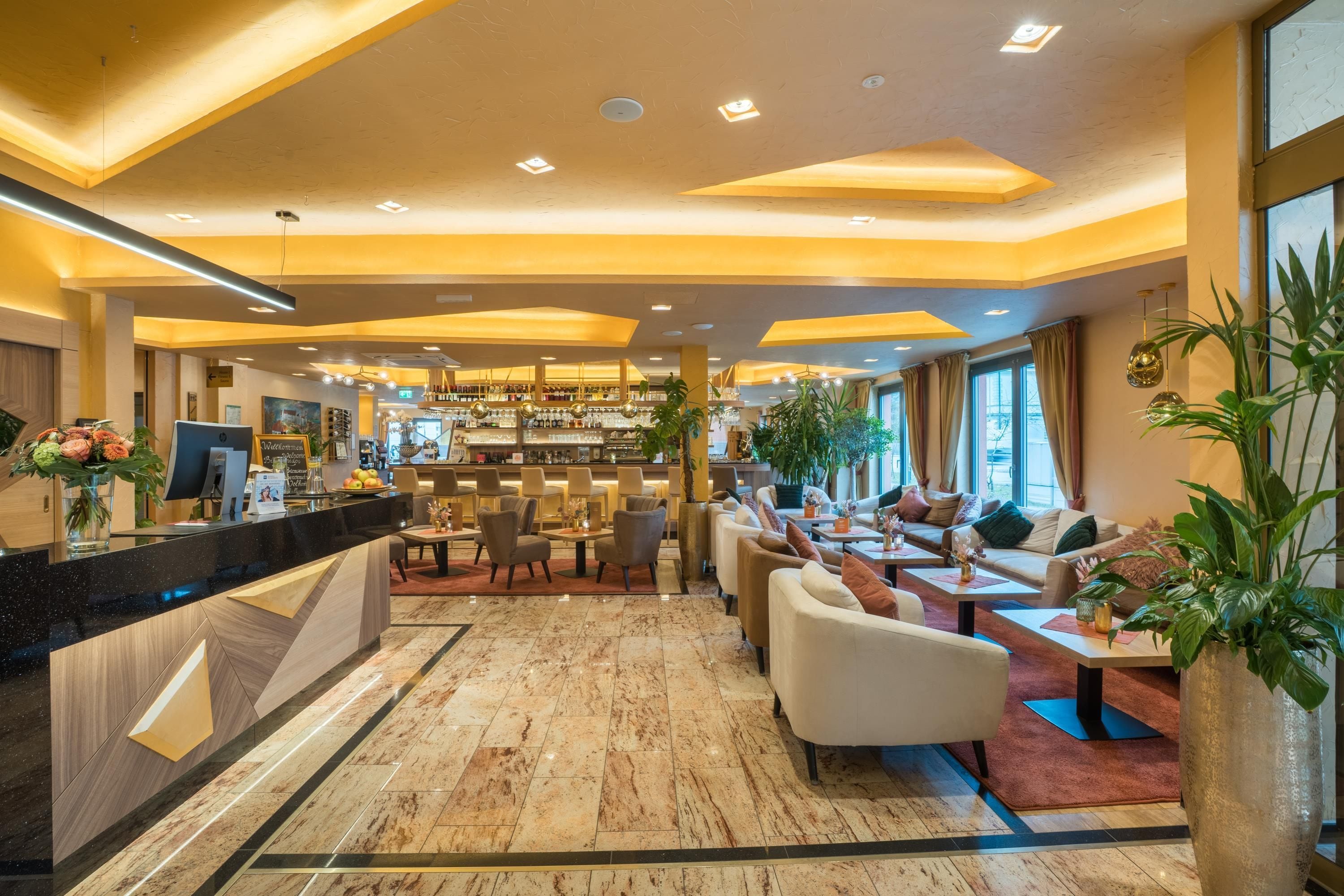 Un vestíbulo de hotel con mostrador de recepción, zona de estar y bar.