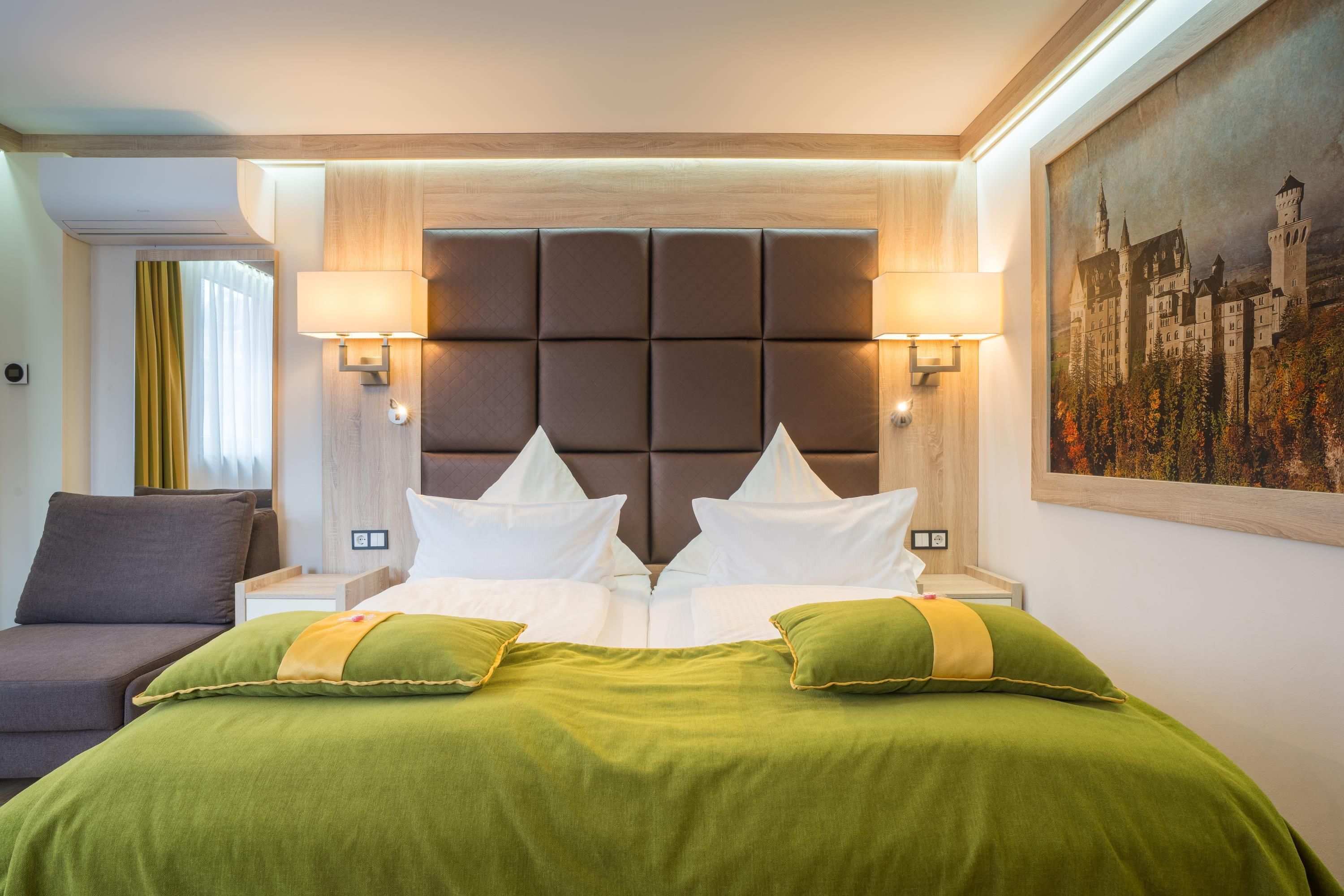 Una camera d'albergo con un letto grande, due comodini, un tavolino e un quadro appeso al muro.