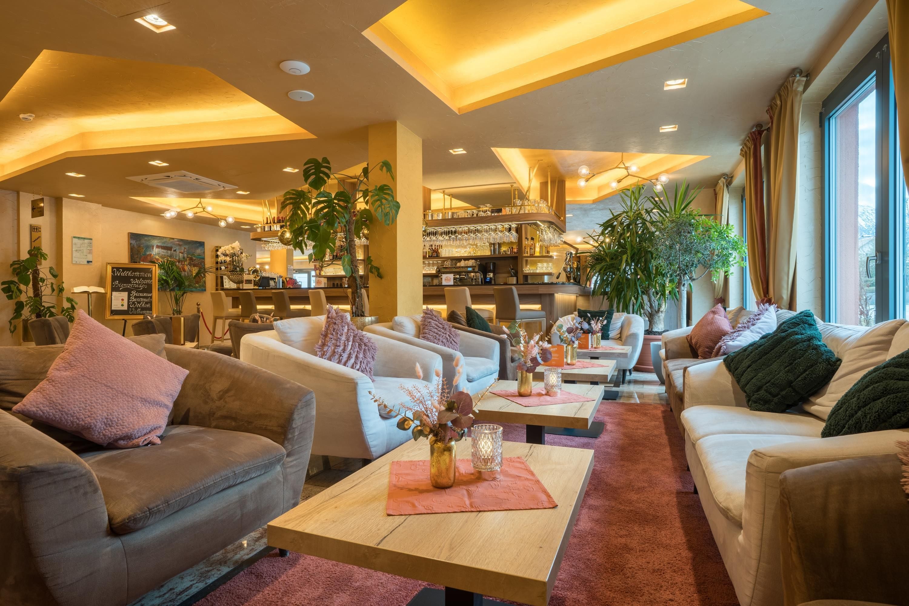 Una hall d'albergo con aree salotto, un bar e la reception.