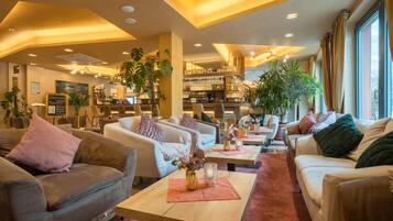 Una hall d'albergo con aree salotto, un bar e la reception.