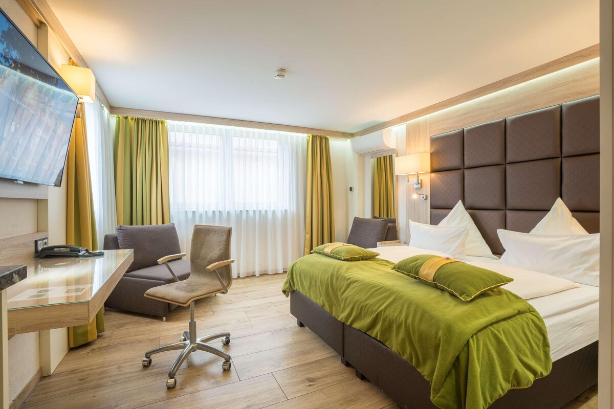 A hotel room with a bed, a desk, a chair, and a television.