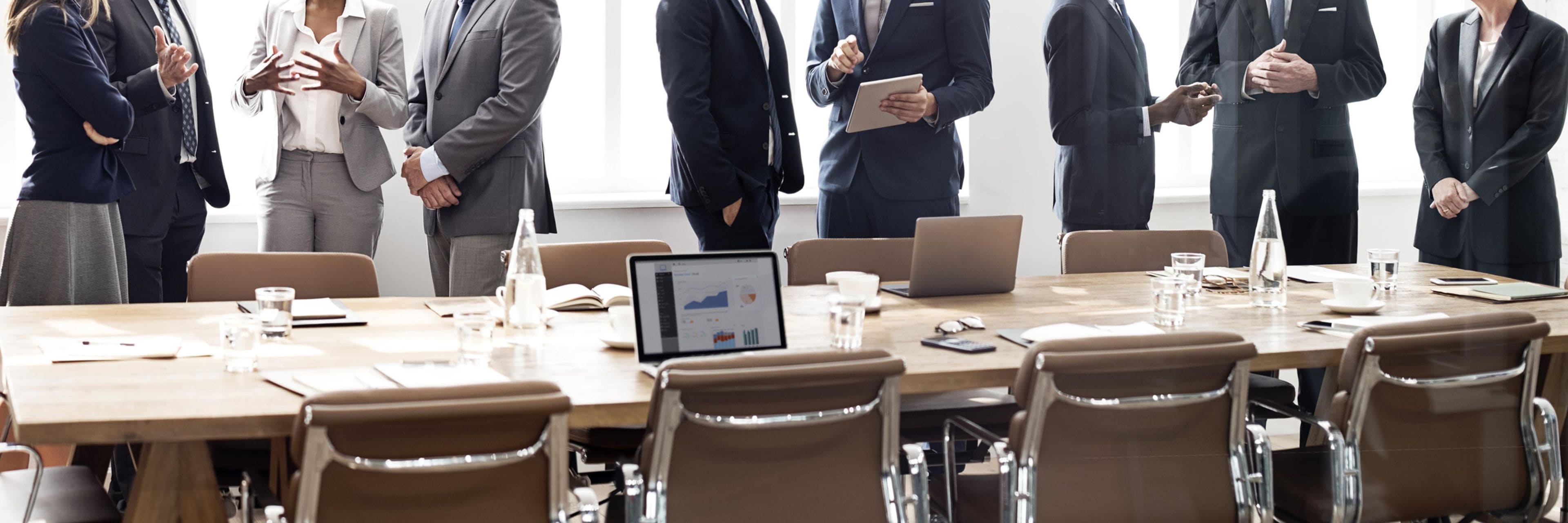 A conference room with a long table, chairs, laptops, and a laptop displaying charts.