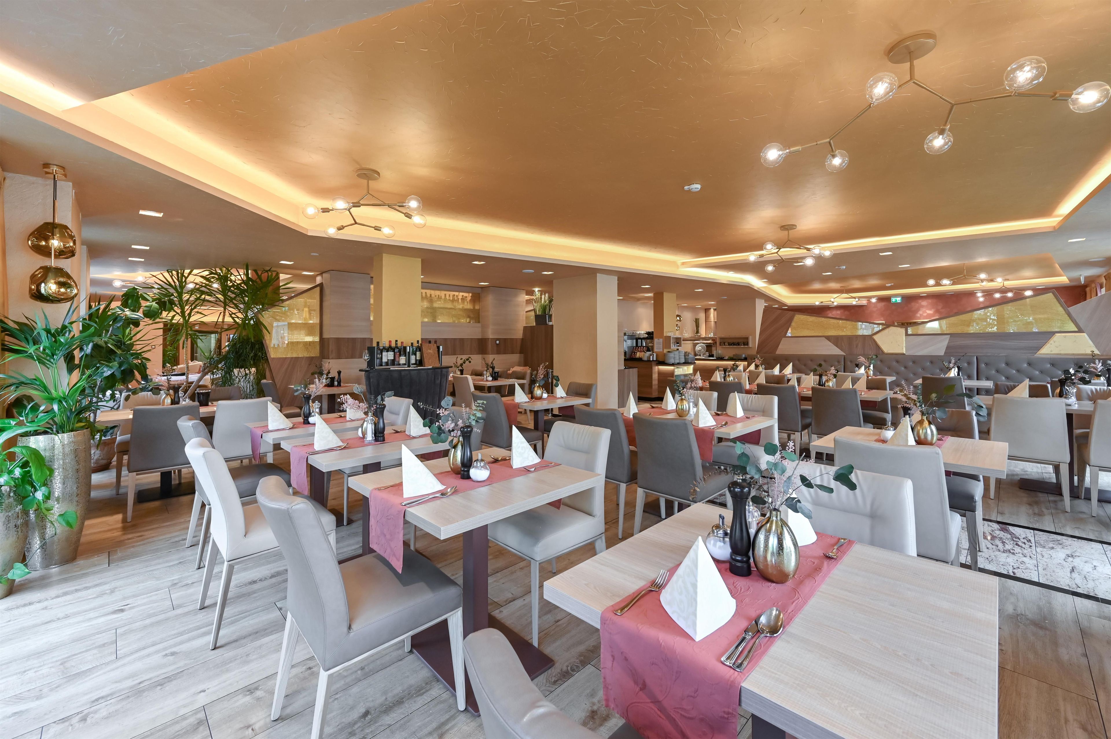 A modern restaurant with multiple dining tables, chairs, and a bar area.