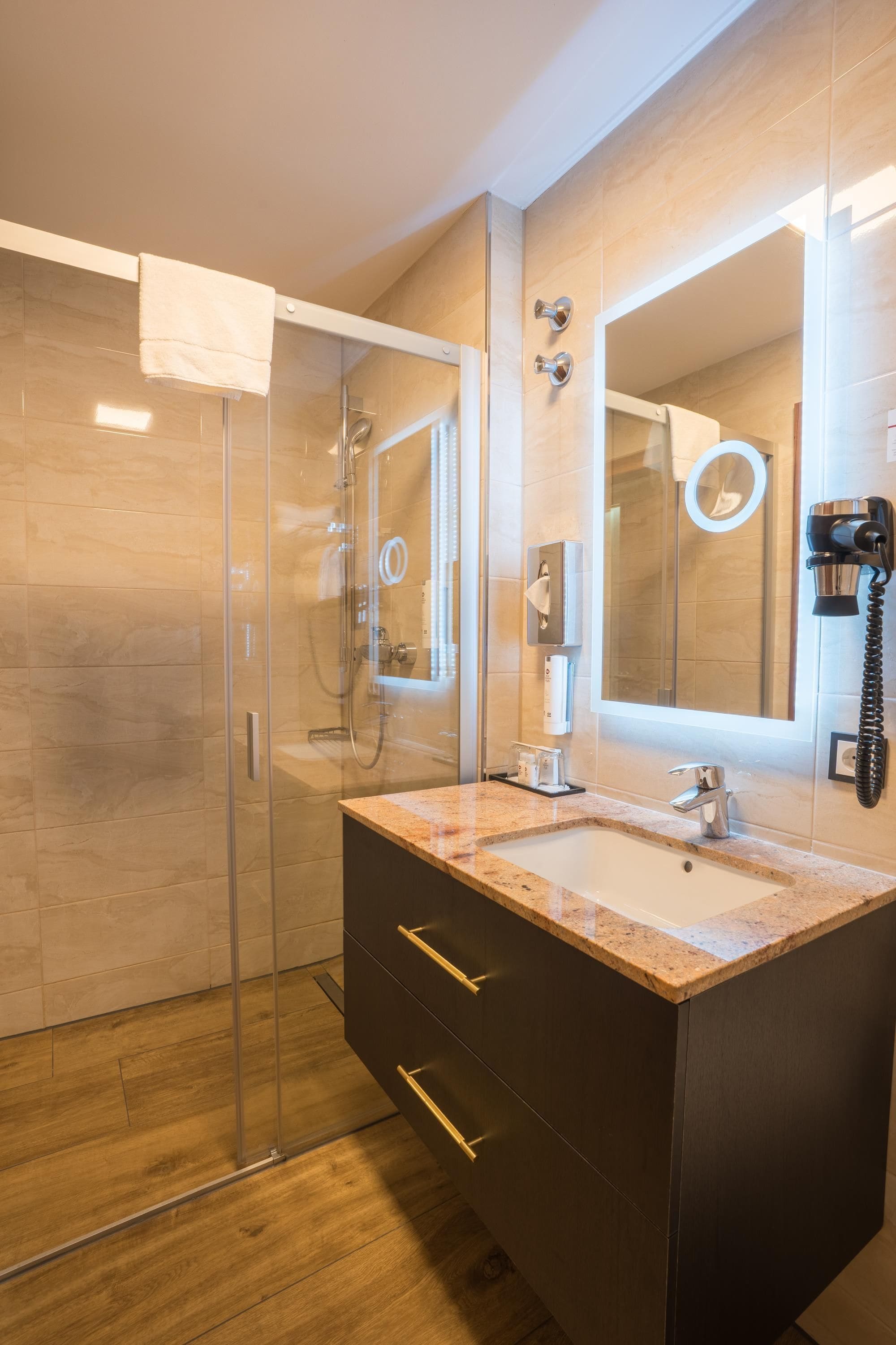 A modern bathroom with a glass shower enclosure, a vanity with a sink, and a large mirror.