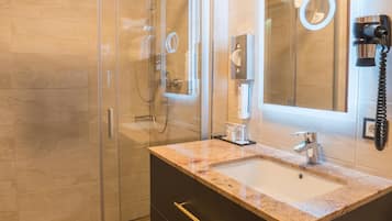 A modern bathroom with a glass shower enclosure, a vanity with a sink, and a large mirror.