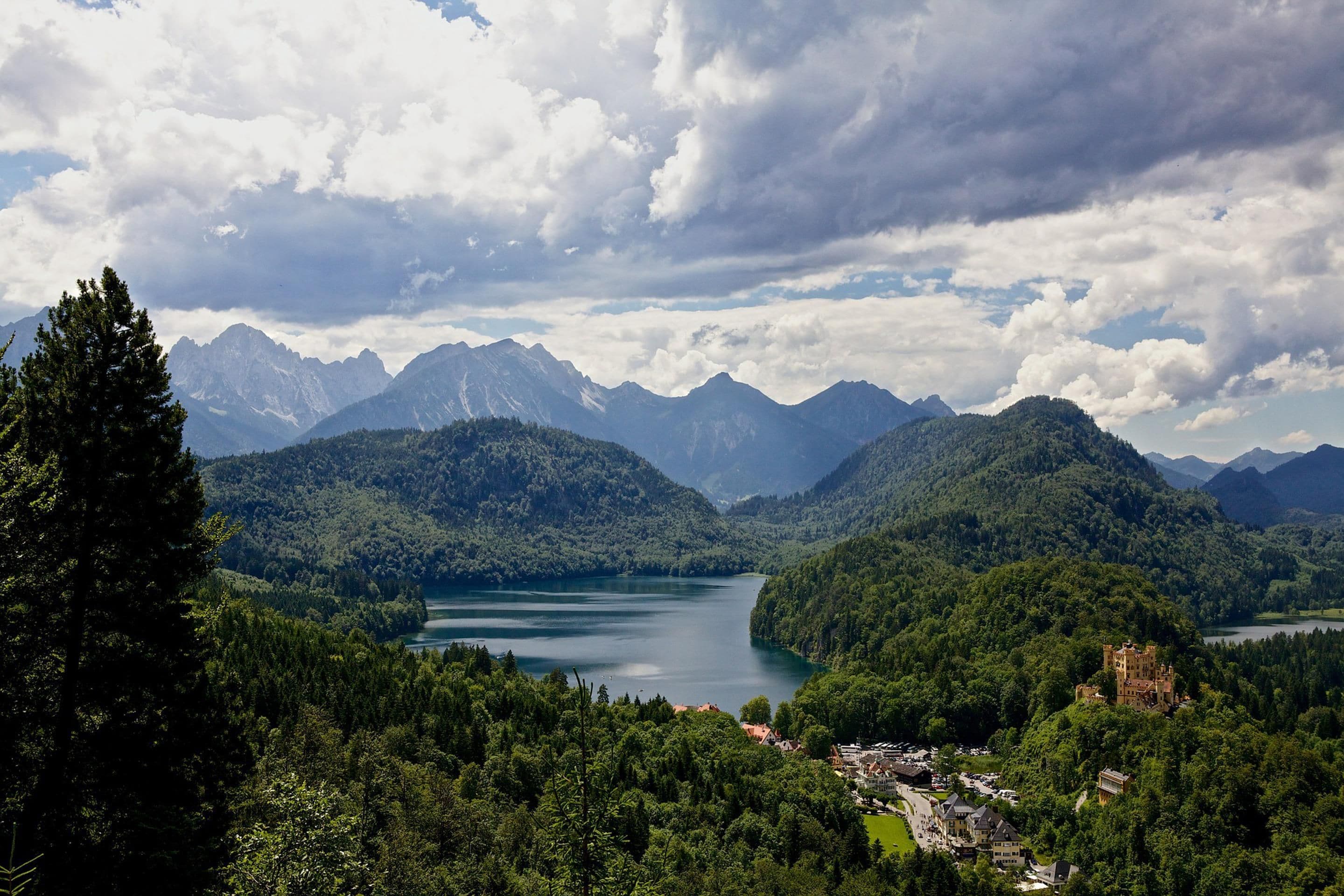 A mountainous landscape with a lake, forested areas, and a castle-like structure.