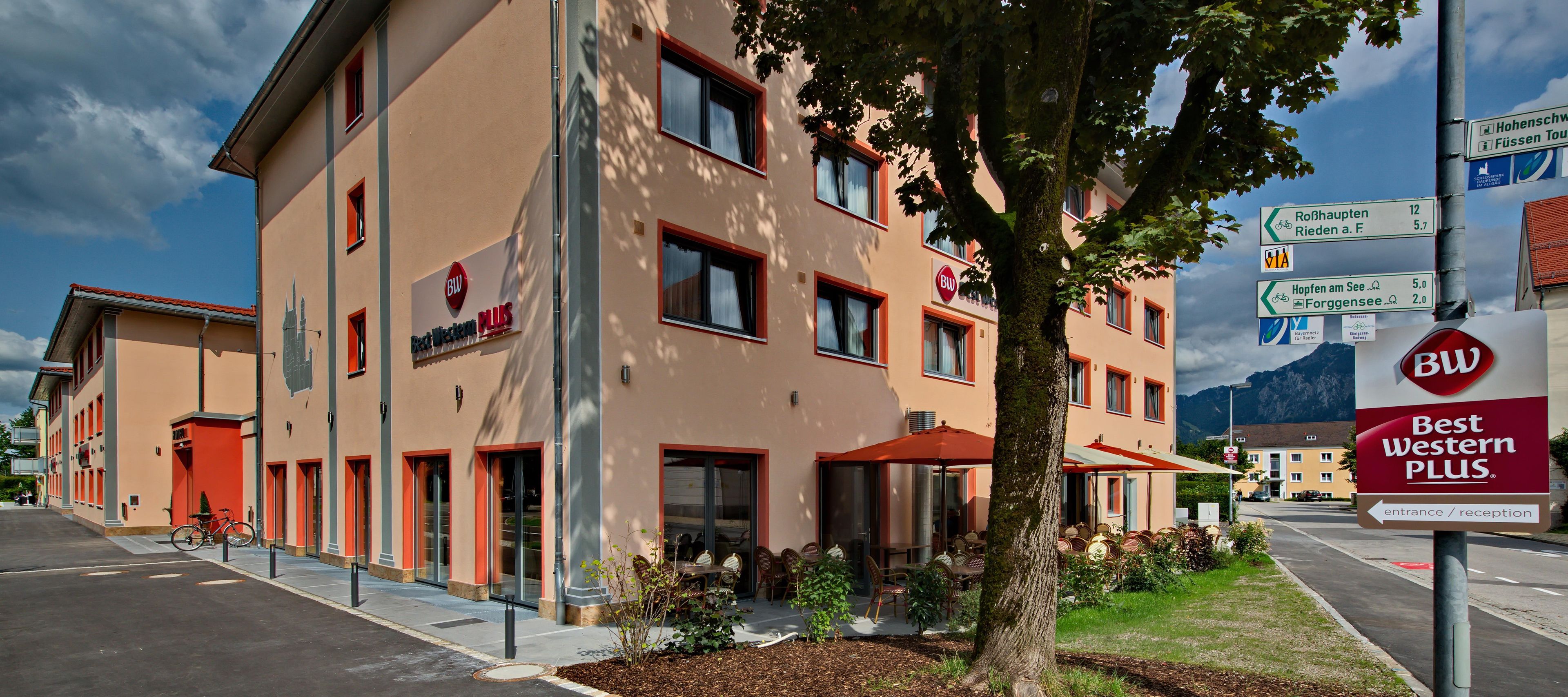 Un hôtel arborant l’enseigne « Best Western Plus », doté de nombreuses fenêtres et d’un panneau indiquant les directions pour se rendre aux lieux d’intérêt à proximité.