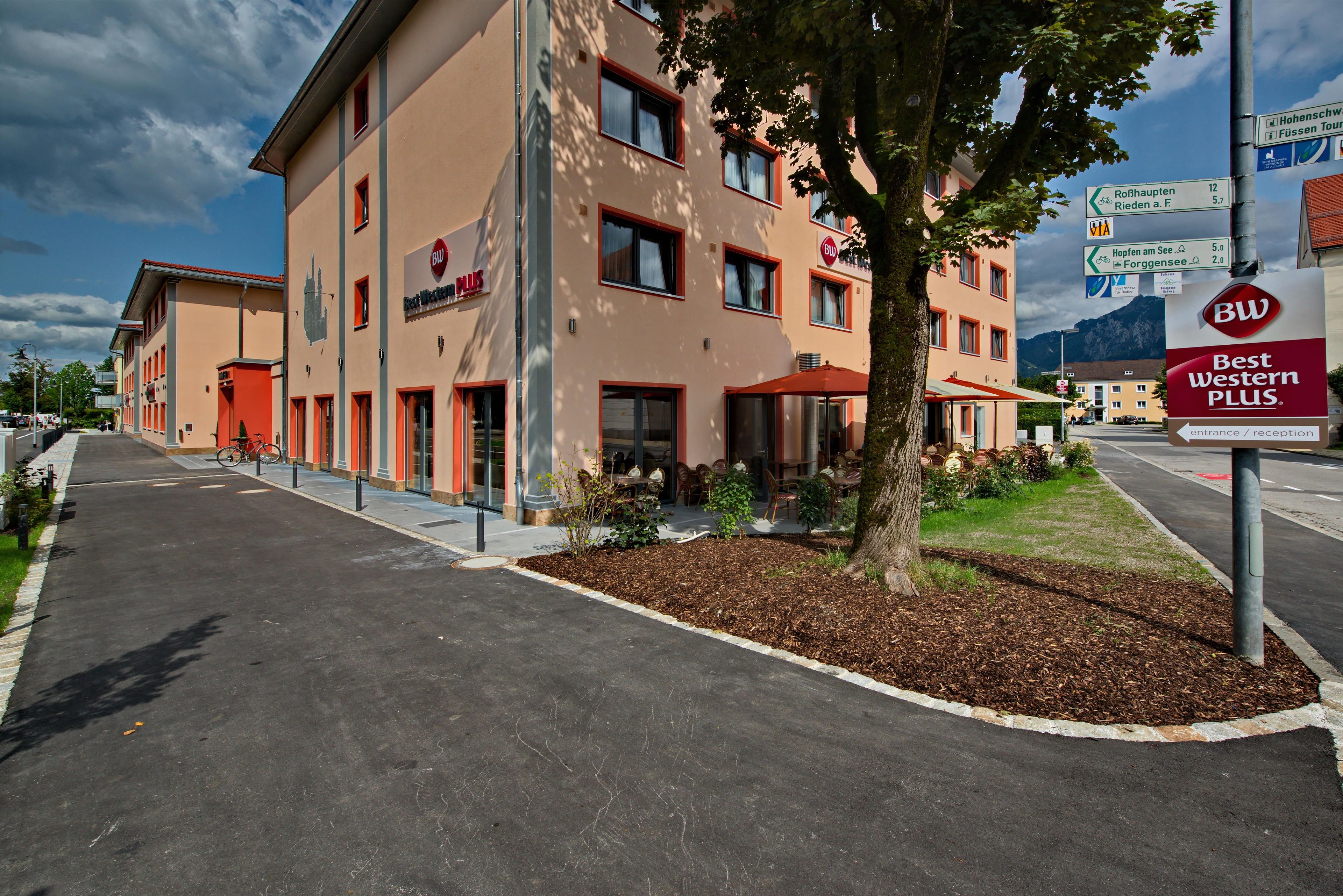 Ein Hotel mit roter und beiger Fassade, einem Schild für Best Western Plus und blauem Himmel.
