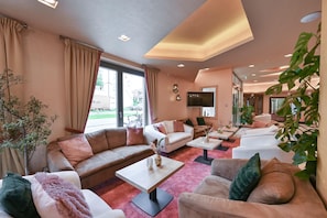 Una sala de estar moderna con un sofá, sillones, una mesa de centro y un televisor.