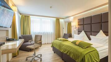 Una habitación de hotel con cama, escritorio, silla y televisor.