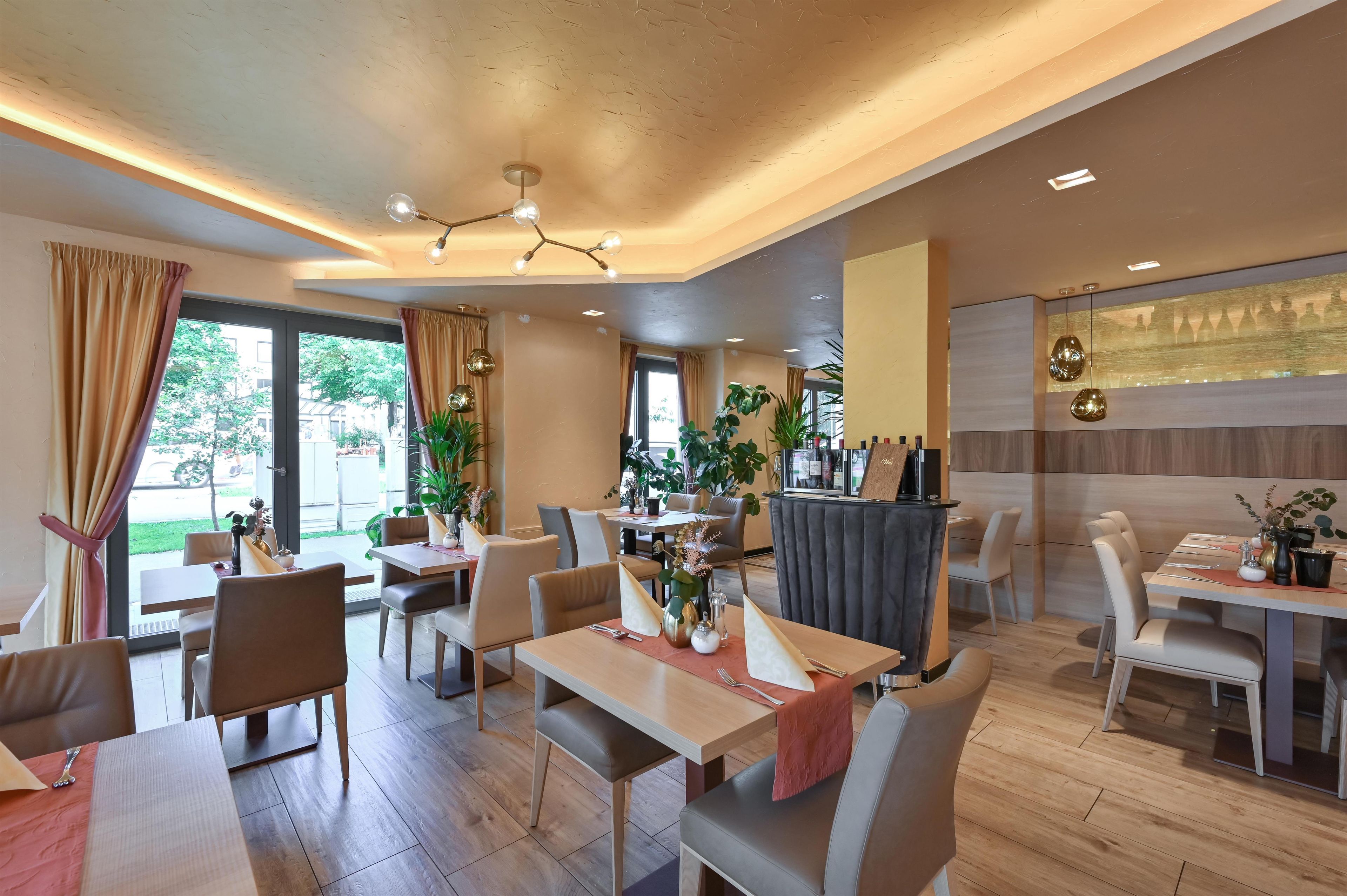 Ein moderner Essbereich mit Holztischen und -stühlen, Topfpflanzen und einer Bar mit einer Glasvitrine.