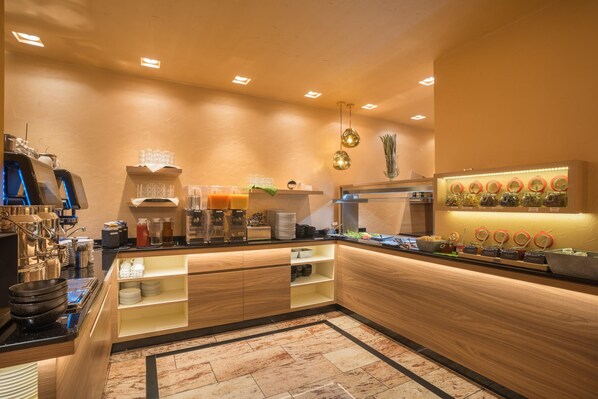Cocina moderna con una isla central, equipada con cafetera, estación de té y diversos alimentos.