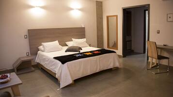 A modern hotel room with a large bed, bedside tables, a desk, and a chair.