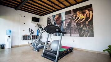 A gym with treadmills, stationary bikes, and a large exercise ball.