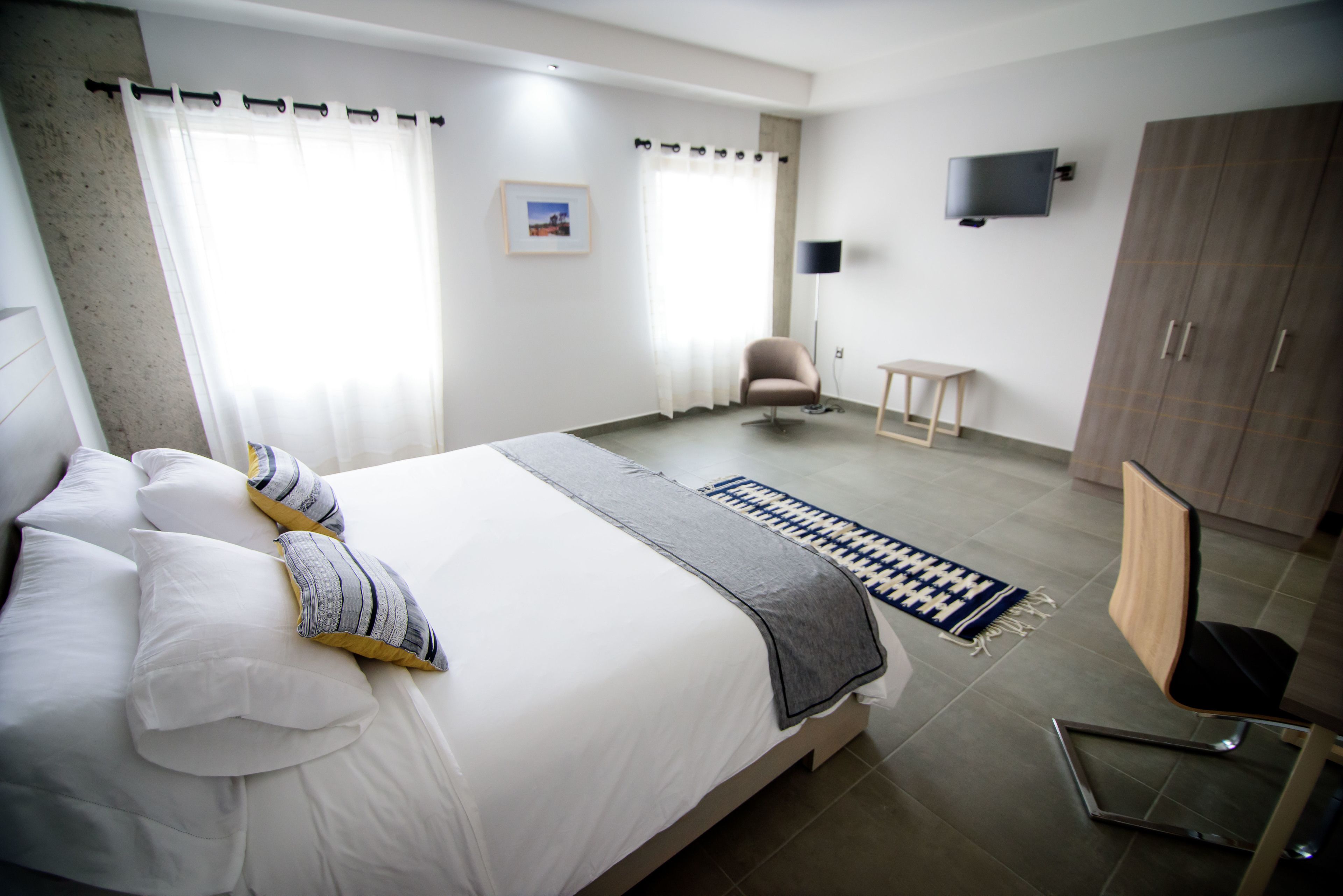 Une chambre d’hôtel moderne dotée d’un grand lit, d’un téléviseur à écran plat fixé au mur, d’une armoire et d’une petite table.