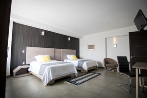Una habitación de hotel moderna con dos camas, un escritorio, una silla y un televisor.