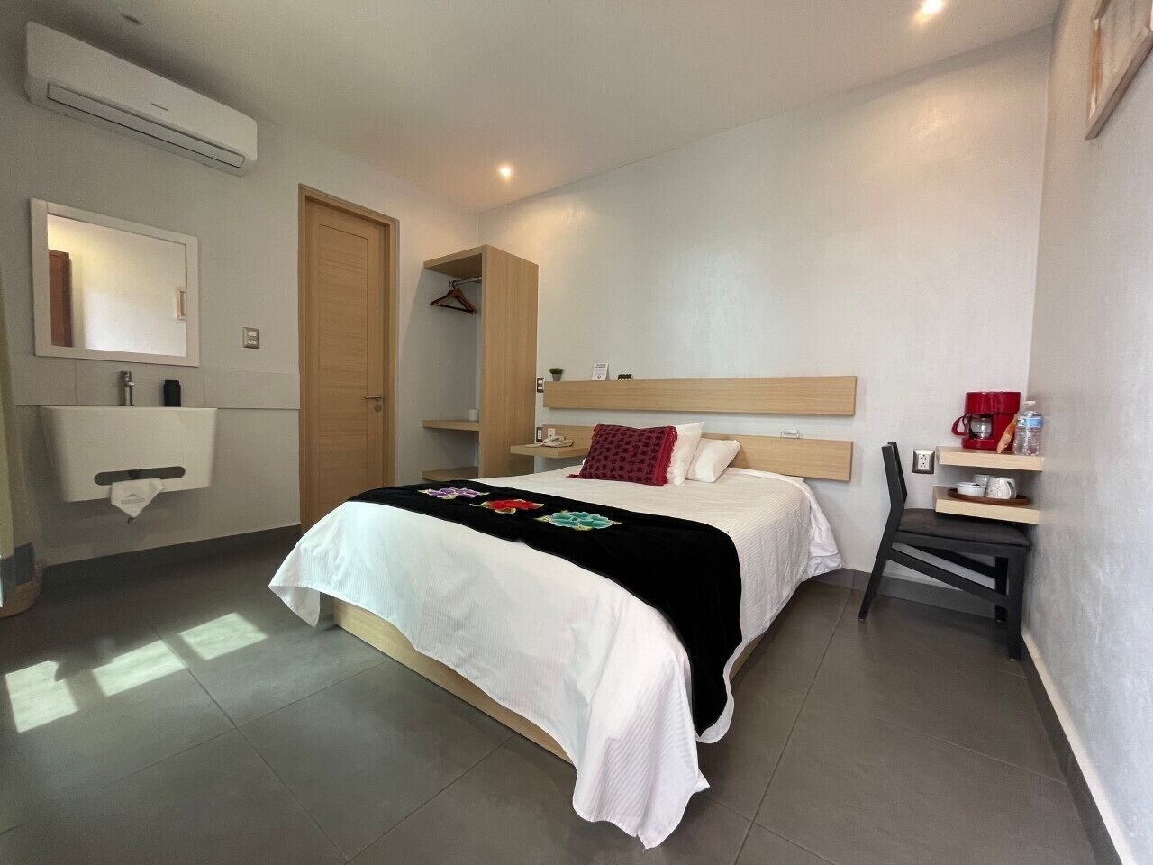 A bedroom with a bed, bedside table, chair, and a small desk with a chair.