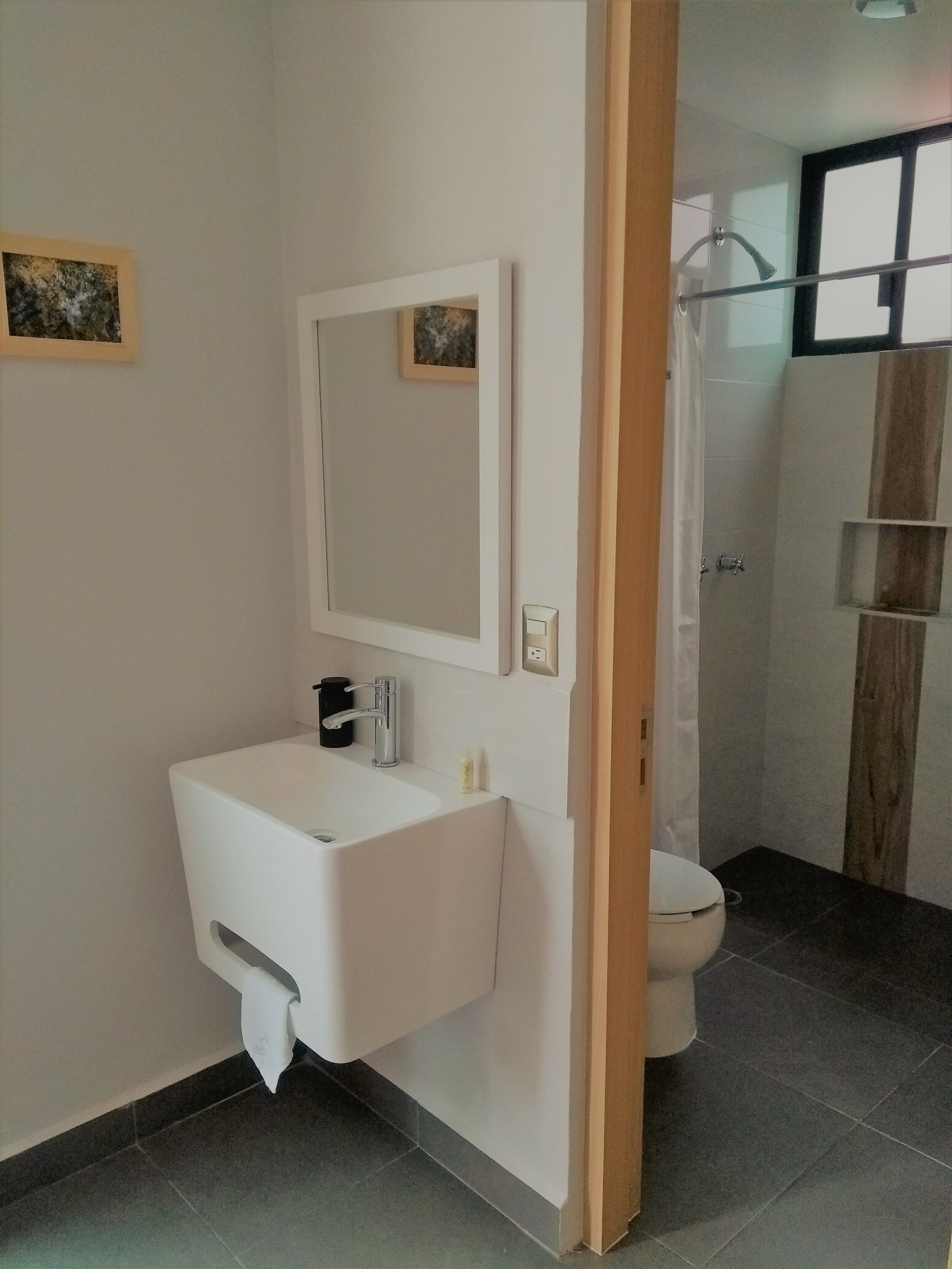 Un bagno moderno con lavandino, specchio e water bianchi.