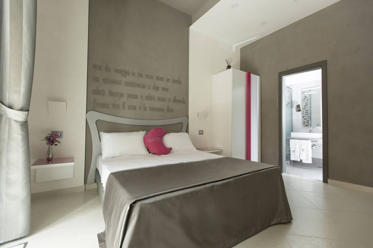 Une chambre moderne avec un lit, une table de chevet et un mur orné d’un texte.