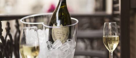 A table set with a bottle of champagne, ice, and glasses, with a plate of food and cutlery.