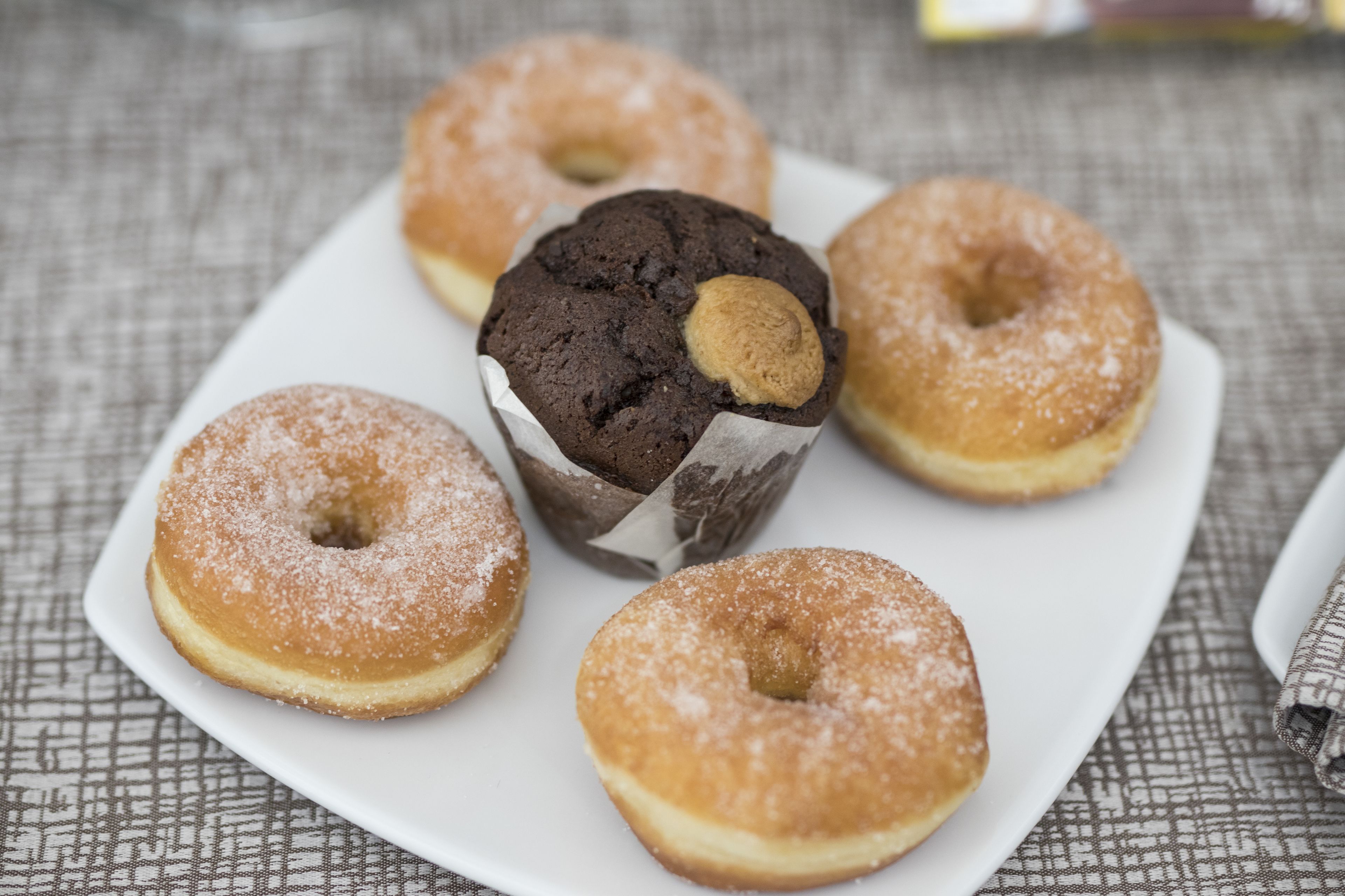 Un plato con cinco rosquillas, una de ellas es un muffin de chocolate con relleno visible.