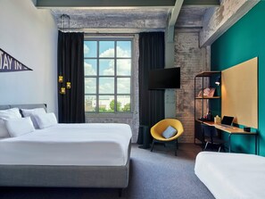 A hotel room with a large bed, a desk with a chair, a TV, and a window with curtains. - The Social Hub Maastricht (Maastricht)