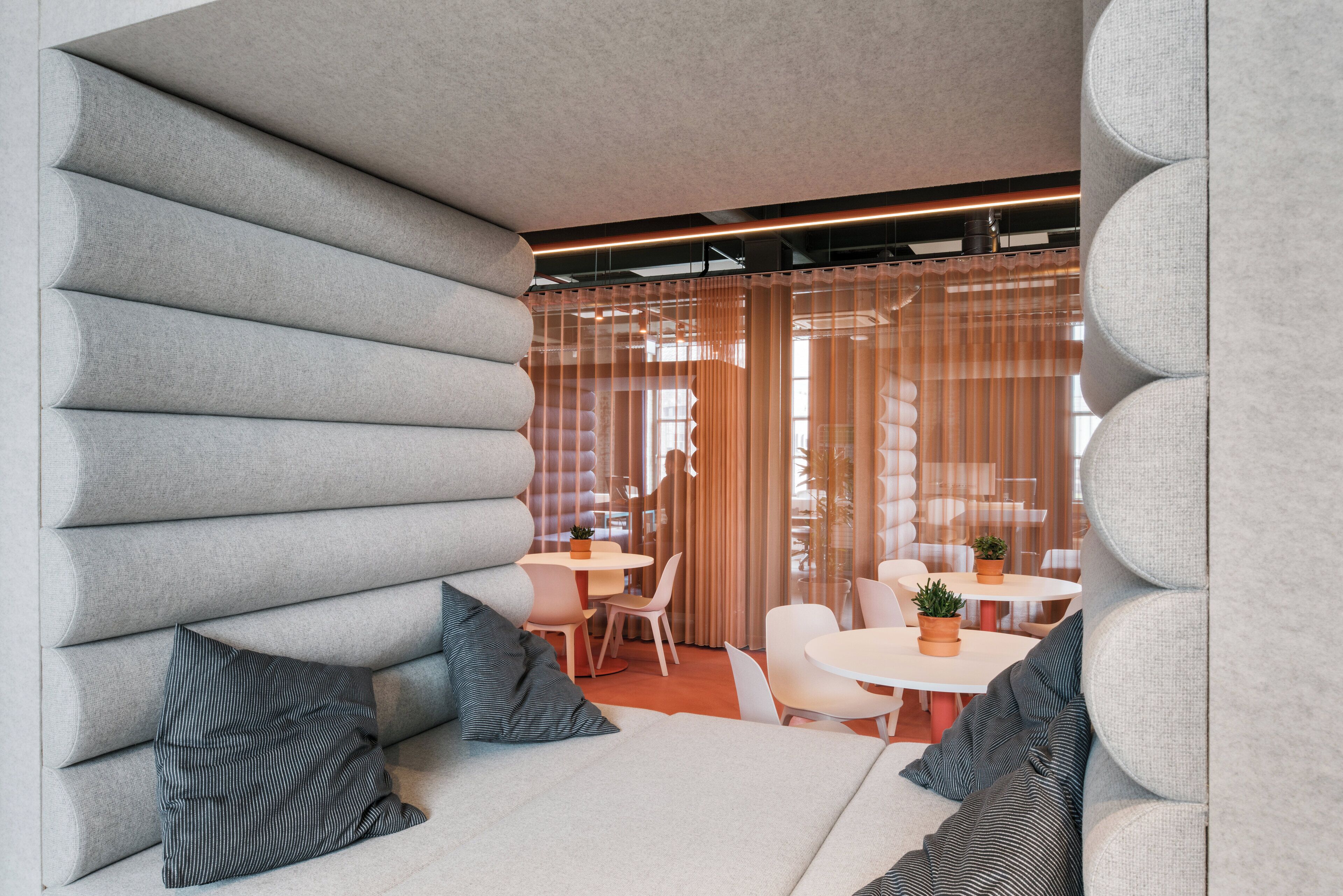 Un intérieur moderne avec un canapé, des coussins à rayures et un coin repas comprenant des tables et des chaises.