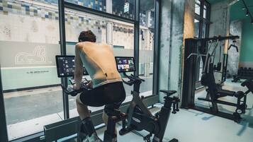 A gym with exercise bikes, a mirrored wall, and large windows overlooking a cityscape.