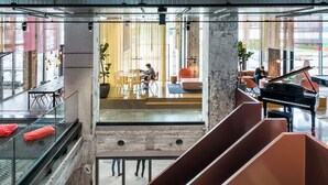 Un interior amplio con un piano, zonas de estar y una escalera.