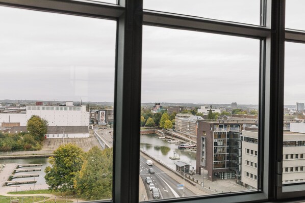 Vista a través de una ventana de un paisaje urbano con edificios, un río y un puente.