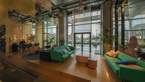 Un vestíbulo espacioso con mobiliario moderno, ventanas amplias y plantas de interior.