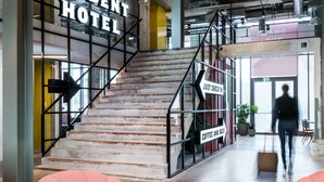 Una escalera con un cartel que dice "Just Checkin" que lleva a una habitación con la leyenda "Café y Cerveza".
